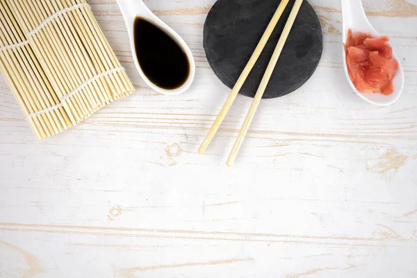 Japon mutfak arka planı bambu hasırı, yemek çubuğu, soya sosu ve turşulu zencefil.