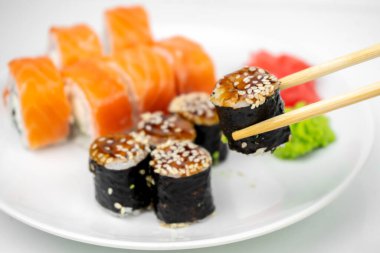 Philadelphia maki rolleri ve soya soslu yılan balığı unagi maki, pembe zencefil, beyaz arka planda wasabi, Asya yemekleri, Japon suşi seti.