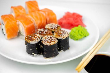 Philadelphia maki rolleri ve soya soslu yılan balığı unagi maki, pembe zencefil, beyaz arka planda wasabi, Asya yemekleri, Japon suşi seti.