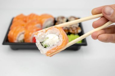 Plastik kaplarda suşi, Philadelphia dürümleri, unagi maki, soya sosu, pembe zencefil, wasabi, suşi teslimat konsepti...