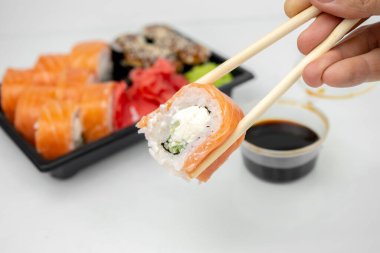 Plastik kaplarda suşi, Philadelphia dürümleri, unagi maki, soya sosu, pembe zencefil, wasabi, suşi teslimat konsepti...
