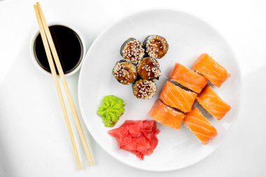 Philadelphia maki rolleri ve soya soslu yılan balığı unagi maki, pembe zencefil, beyaz arka planda wasabi, Asya yemekleri, Japon suşi seti, üst manzara