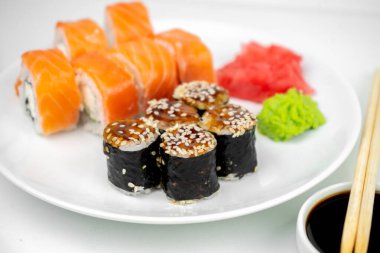 Philadelphia maki rolleri ve soya soslu yılan balığı unagi maki, pembe zencefil, beyaz arka planda wasabi, Asya yemekleri, Japon suşi seti.