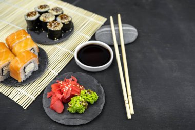 Philadelphia maki rolleri ve soya soslu yılan balığı unagi maki, siyah arka planda pembe zencefil, wasabi, Asya yemekleri, Japon suşi seti.