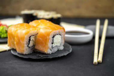 Philadelphia maki rolleri ve soya soslu yılan balığı unagi maki, siyah arka planda pembe zencefil, wasabi, Asya yemekleri, Japon suşi seti.