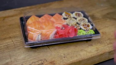Plastik kaplarda suşi, Philadelphia dürümleri, unagi maki, soya sosu, pembe zencefil, wasabi, suşi teslimat konsepti...