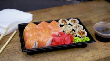 Bir Philadelphia maki rulosu al ve soya sosunun içine koy. Pembe zencefil, siyah taş tabakta wasabi, Asya yemeği, Japon mutfağı.