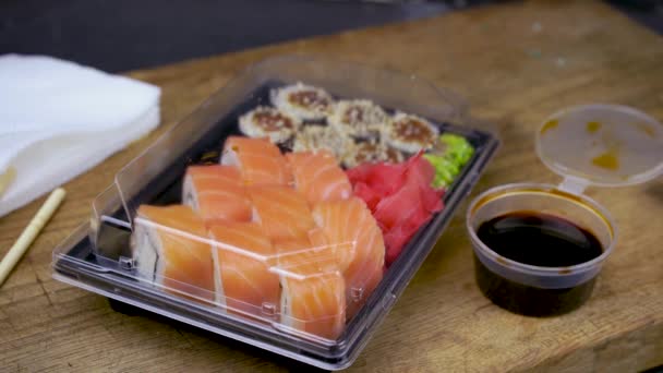 Take a philadelphia maki rolls with bamboo chopsticks and put in into soy sauce. pink ginger, wasabi on black stone plate, asian food, japanese cuisine delivery — Stock Footage Take Philadelphia Maki Rolls Bamboo Chopsticks Put Soy Sauce Pink Video Clip