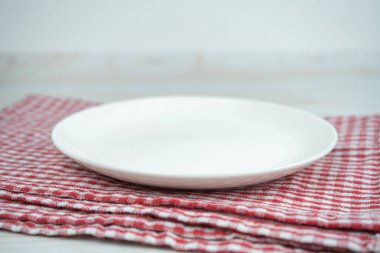 Kırmızı mutfak havlusunda beyaz, boş seramik tabak..