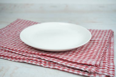 Kırmızı mutfak havlusunda beyaz, boş seramik tabak..