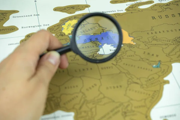 Looking for the country on a map with a magnifying glass. Ukraine on a map