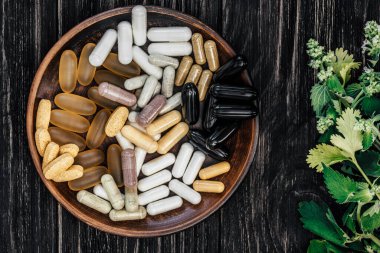 Multivitamin pills on a clay plate, on a vintage wooden table, with a sprig of mint clipart