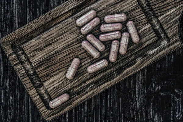 Ahşap bir tahtanın üzerinde, eski bir ahşap masanın üstünde, en iyi görünümde multivitamin hapları.