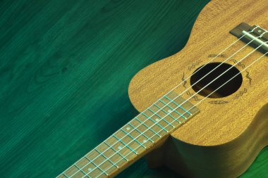 Yeşil ahşap bir masanın üzerinde bir ukulele yatıyordu. Kendi başlıklarınızı eklemek için kopyalama alanı olan bir müzik arkaplanı