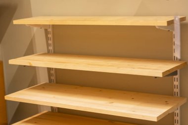 Duvardaki ahşap raflar yakın plan. Gardıropta depo için raflar. Hafif doğal ahşaptan yapılmış yeni raflar.