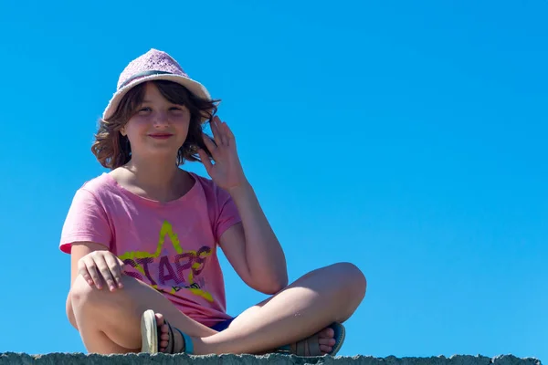 Uma Menina Chapéu Rosa Senta Uma Posição Lótus Contra Céu — Fotografia de Stock