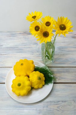 Ahşap masadaki sabır ve vazodaki sarı çiçekler. Boşluğu kopyala, seçici odak.