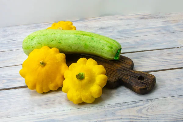 Zucchini and yellow mini patty pan squashes on wooden table close-up. Healthy food concept.