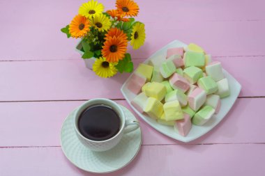 Pembe ahşap arka planda güzel bir kahvaltı. Bir fincan kahve ve marşmelov. Romantizm ve şefkat kavramı.