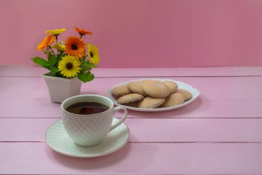 Kahvenin romantik kahvaltısı ve lezzetli bisküviler. Pembe tahta arkaplan, seçici odak.