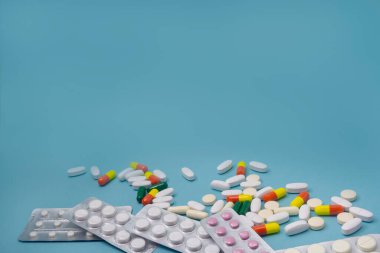 Aspirin ve antibiyotik haplar, mavi arka planda vitamin kapsülleri. Uzayı kopyala Sağlık, virüs ve hastalıklardan korunma kavramı.