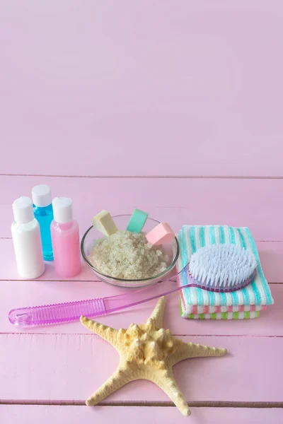 Means for spa treatments for skin cleansing with sea salt with minerals Massage brush and natural bath cosmetics. Pink background, copy space.