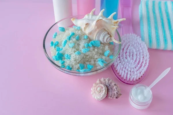 Ölü deniz mineralli tuz ve pembe arka planda masaj fırçası. SPA konsepti, vücut ve deri temizleme, rahatlama.