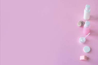 Pembe arka plan, güzellik salonu modeli. Boş etiketli kozmetik şişe kapları. Uzayı kopyala, pastel renkleri. Doğal organik kozmetik konsepti.