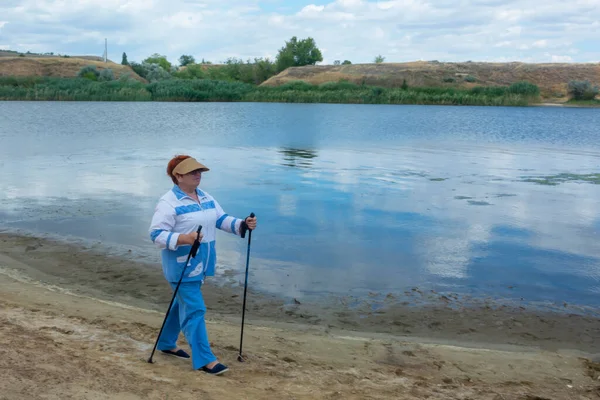 Scandinavisch Wandelen Een Oudere Vrouw Loopt Langs Oever Van Rivier — Stockfoto