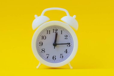 Beyaz alarmlı saat 12 saat 15 dakika. Parlak sarı arkaplan, boşluğu kopyala.