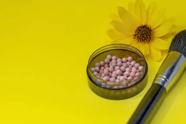 Ball blush and makeup brush close-up. Cosmetics on a bright yellow background, shallow depth of field, blur.