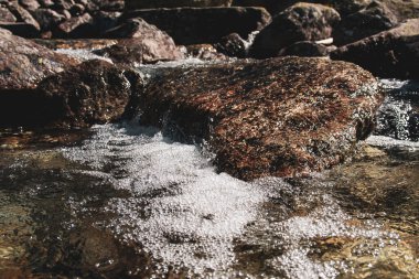 Su, dağ nehrine yerleştirilmiş taşların arasından hızla akıyor..