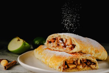  Geleneksel elmalı börek. Koyu arkaplanda iki dilim elmalı turta. Turta üzerinde pudra şekeri.