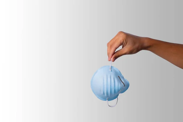 Tıbbi maske takan Latin bir adamın eli beyaz arka plana düşmek üzere. Hapsedilmenin sonu. Boşluğu Kopyala