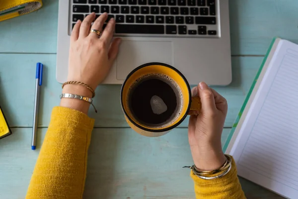 Umman 'ın evden ders çalışmasının seçmeli odağı bir fincan kahve tutuyor. Ev eğitimi kavramı.