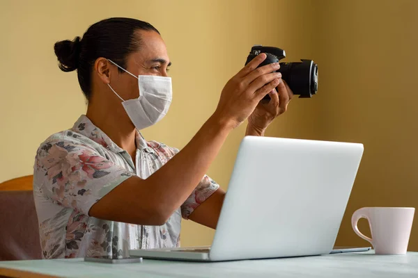 Tıbbi maskeli Latin fotoğrafçı evde çalışıyor. Uzayı kopyala Coronavirus konsepti.