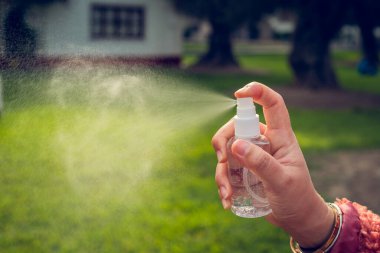 Dışarıda sprey kullanan genç bir kadının eli. Coronavirus konsepti. Boşluğu kopyala.