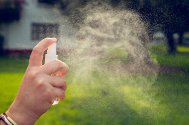 Dışarıda sprey kullanan genç bir kadının eli. Coronavirus konsepti. Boşluğu kopyala.
