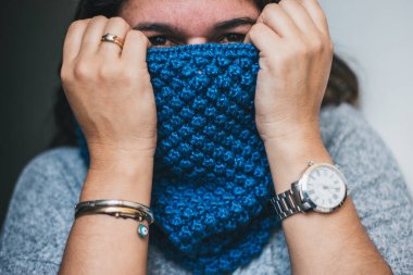 Soğuk kıştan yüzünü örten kadın, el örgüsü bir eşarpla eğleniyor. kış mevsimi