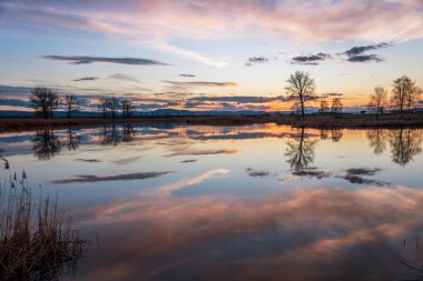 Sakin göl üzerinde gün batımı, kışın suda gökyüzü yansıması..