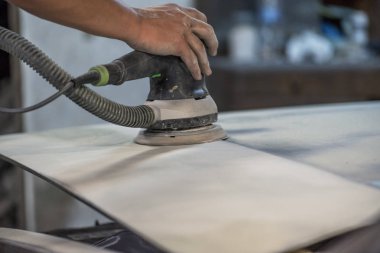 Araba tamirhanesinde araba cilalayan bir adamın elinde öğütücü..