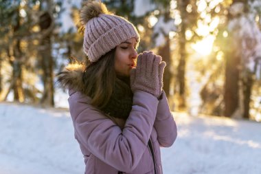 Yakın çekim Sunset'teki kış ormandaki güzel genç kadın portresi.