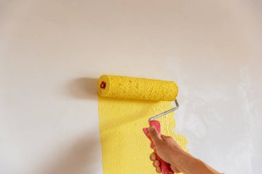 Dekoratörün el boyası silindirle duvarı.