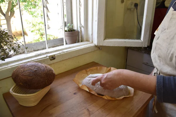 一个女人烤了一块新鲜的土制面包 土制土司酸面包放在木制切碎板上 一片褐色的面包 切好的面包高质量的照片 — 图库照片