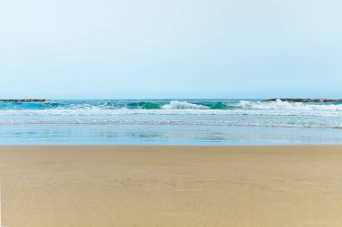 Okyanusun yanında kumlu bir sahil. Derin turkuaz berrak suyu olan sakin ve sessiz bir sahil. Dalgalar dalgaların üzerine düşüyor. İz bırakmadan yumuşak, altın deniz kumu. Gökyüzünün su üzerindeki yansıması. Ufuk çizgisi açık. Yüksek kalite fotoğraf