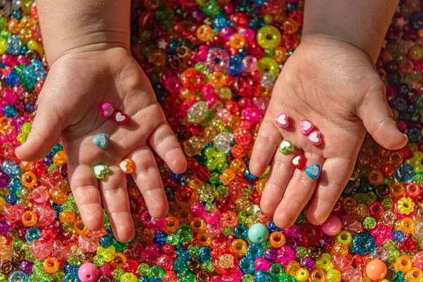 Una mano de las niñas sostiene cuentas en forma de corazón de color — Foto de Stock