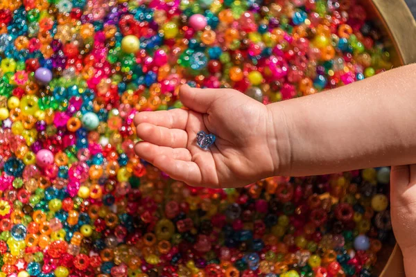 Dziewczęca ręka trzyma kolorowe koraliki w kształcie serca — Zdjęcie stockowe