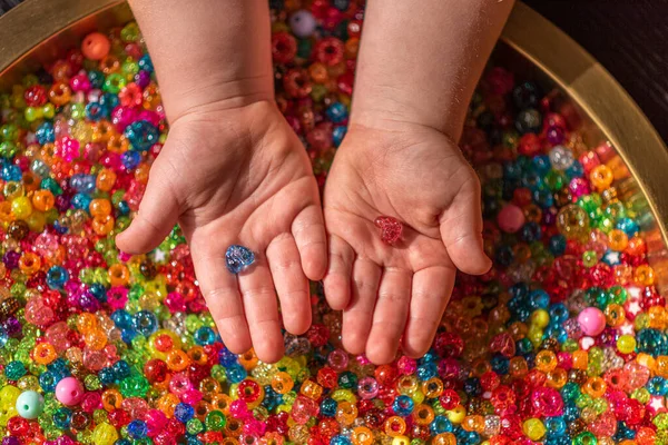 Una mano de las niñas sostiene cuentas en forma de corazón de color —  Fotos de Stock