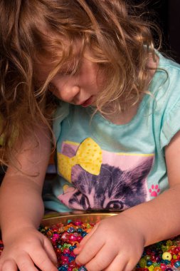 Bir çocuk renkli ve parlak boncuklarla oynar