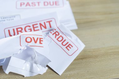 Gecikmiş faturalarla toplanan borç mektupları ve masadaki son duyurular. Kırmızı yazılar ekonomik işsizliğe karşı mücadeleyi temsil ediyor.